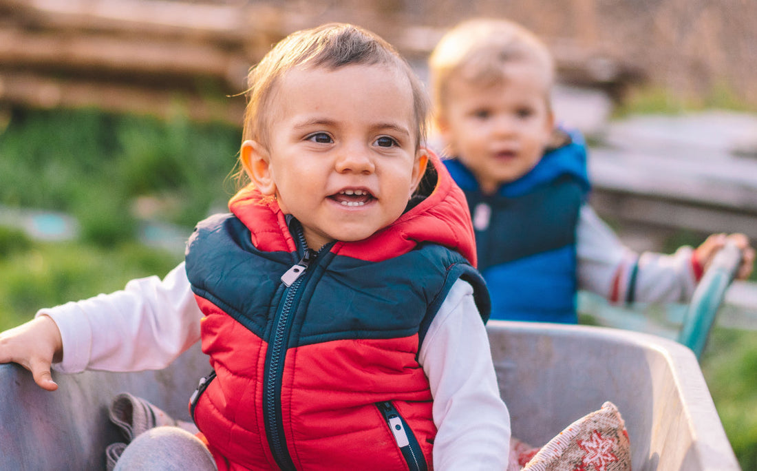 Two young children enjoying outdoor play together in a natural setting.