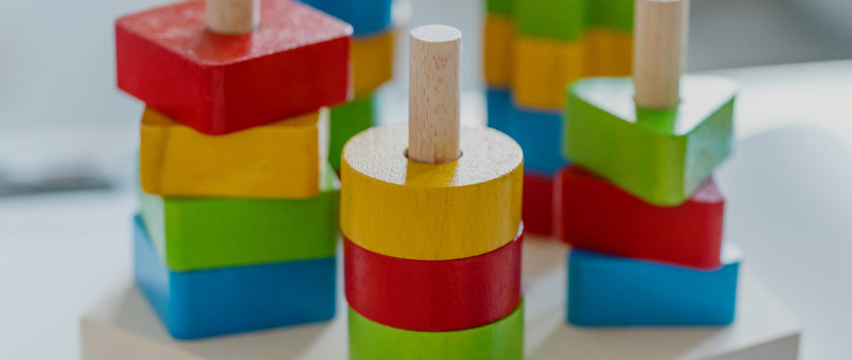 Childhood development center affiliate-therapists - Colorful wooden stacking toys designed to develop fine motor skills and hand-eye coordination in young children.