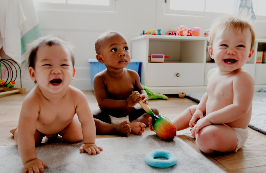 Early intervention program right your child - Three smiling babies playing together in an early childhood development setting.