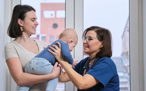 Early intervention program stimulation - Pediatric therapist examining a baby held by his mother.
