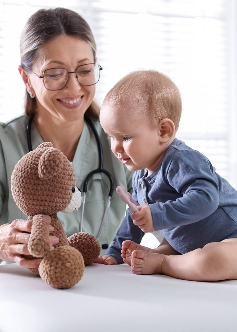 Pediatric therapist engaging a baby in early intervention play with a teddy bear.