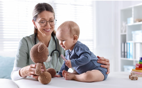 Early intervention programs - Pediatric therapist supporting a baby's development through play with a teddy bear.
